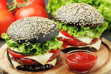 Two black burgers with vegetables and beef meat