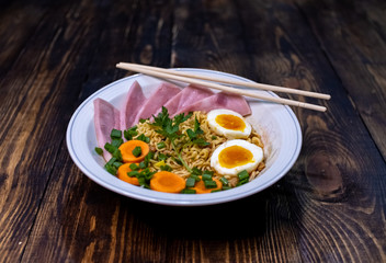 A plate of Japanese ramen with chopsticks stands on a wooden table. Japanese ramen. Wooden background. Traditional asian dinner. Delicious dinner. Asia traditional food. Food preparation.