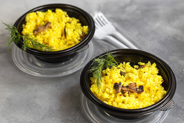 Italian risotto with champignons and parmesan. Food is delivered to your home in quarantine in disposable utensils. Rice is seasoned with turmeric and herbs. Copy space