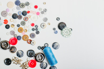 Threads and buttons of different colors on a white background.