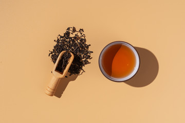 Ceramics bowl with black puer tea ,dry pu-erh tea leaves in a wooden bamboo plate on a beige...