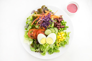 vegetable salad top with boiled egg in white plate  served with red dressing in a dipping bowl