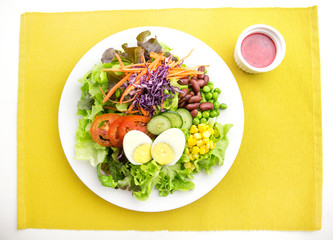 vegetable salad top with boiled egg in white plate  served with red dressing in a dipping bowl