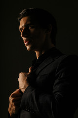 Business man dressed in black suit portrait against a dark background. Closeup portrait handsome man,