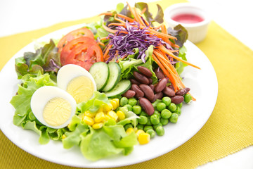 vegetable salad top with boiled egg in white plate  served with red dressing in a dipping bowl