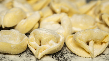 Fototapeta na wymiar Close up to delicious tortellini a ring-shaped pasta from Italy. Traditionally they are stuffed with a mix of meat, parmigiano reggiano cheese, egg and nutmeg