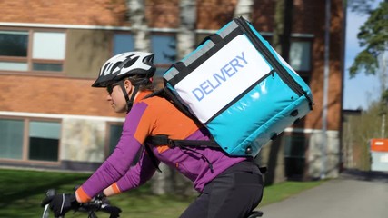 A courier riding a bicycle around the city. Delivery of orders to customers during a pandemic and total quarantine. Tracking shot