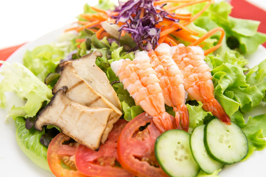 vegetable salad top with shrimps and grilled sliced oringi mushroom in white plate  served 