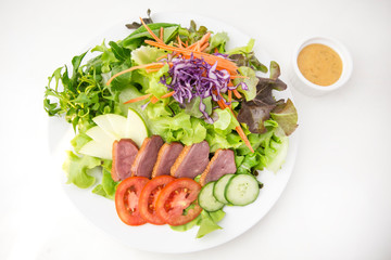 vegetable salad top with sliced roasted duck in white plate isolated white background