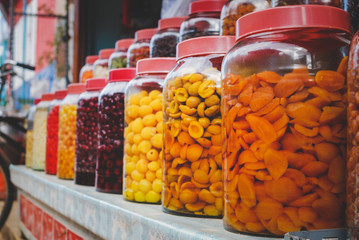 Pickled Fruits in glass jar arranging in the shop shelf.
