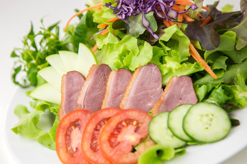 vegetable salad top with sliced roasted duck in white plate