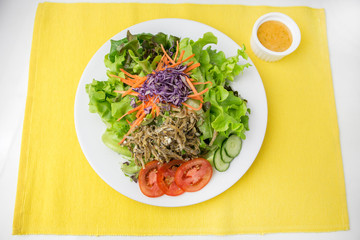 vegetable salad top with fried minnow fish in white plate  served with thousand island dressing in a dipping bowl