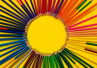 A lot of multi-colored pencils in a circle on a black bright background. School life concept