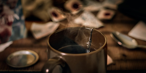 Cup of hot tea in a brown cup by the light of a lamp