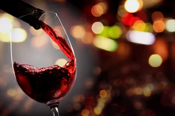 Gordijnen Rode wijn uit de fles in glas gieten © BillionPhotos.com