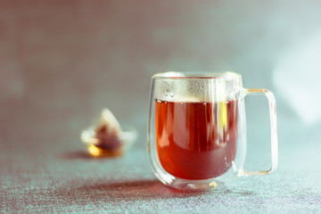 Glass transparent Cup with double walls and brewed tea and a bag in the Cup. Toned. Copy space