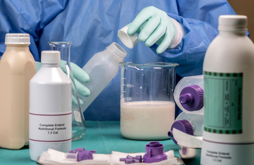 Nurse uncovering bottle of equipment power supply of enteral nutrition, palliative care in hospital, conceptual image