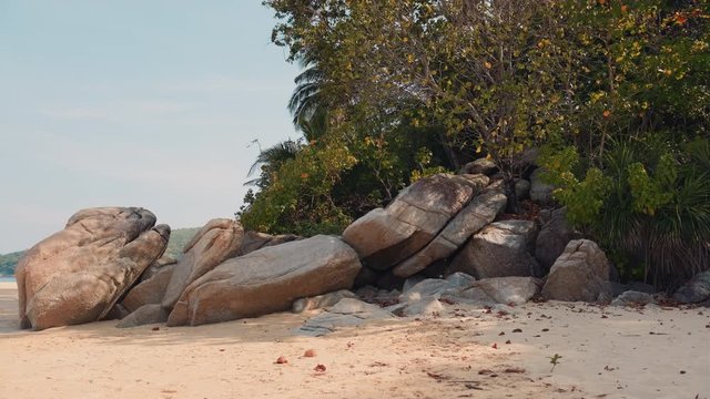 Rocks on an empty sand Nai Thon beach in Phuket, Thailand. Calm and sunny day with clear sky  on a beach. Static shot.