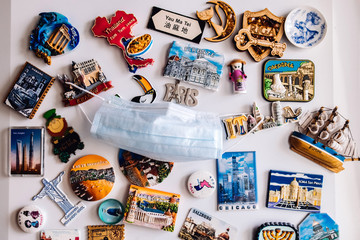 Many magnets on fridge showing several countries on face COVID protection mask 