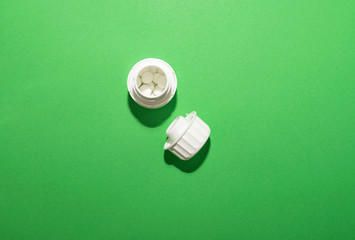 Step 3. A white jar of pills is open with a lid on a green background