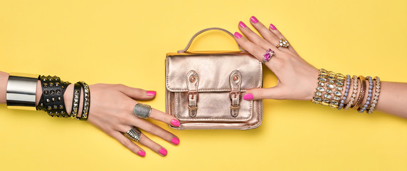 Fashion. Female hand, Stylish jewelry, handbag clutch. Minimal design. Summer hipster woman luxury accessories, bracelets ring. Creative art friendship concept Trendy jewelry on yellow, banner
