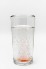 soluble effervescent multivitamin in a glass glass with water on a white background