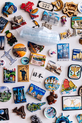 Many magnets on fridge showing several countries on face COVID protection mask 