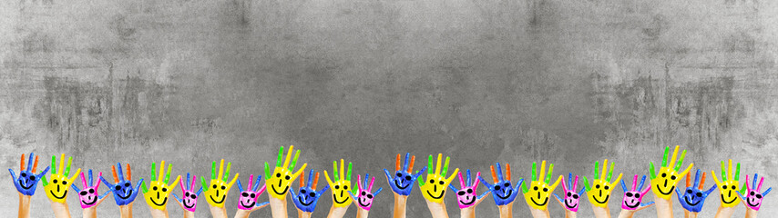 School background background - Many brightly painted children's hands in front of a old aged empty blackboard concrete wall texture, with space for text