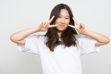 Portrait of young beautiful Asian woman with peace sign