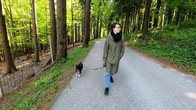 Woman in casual clothes walking with small black dog, footage with action camera