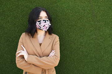 Pretty woman is wearing decorated with flowers face mask on green background - 346591626