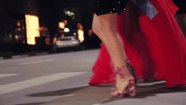 girls in dresses in high heels cross the road at a pedestrian crossing, legs close-up