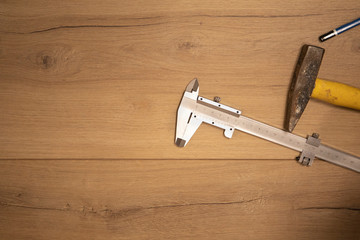 Vernier stainless steel calipers and old hammer on wooden floor with copy space