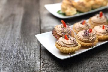 Fototapeta na wymiar Shortbread muffins stuffed with tuna paste. A dry starter. Appetizing dish on a wooden table.