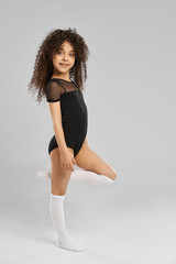 Little female gymnast posing in studio.