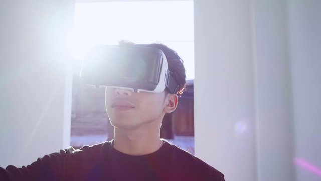 Handsome Man using 3D virtual reality headset.man wearing VR headset in living room.Man touch something using modern 3D vr glasses indoors.