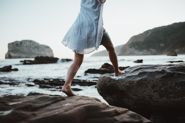 Young woman jumping on rocky beach