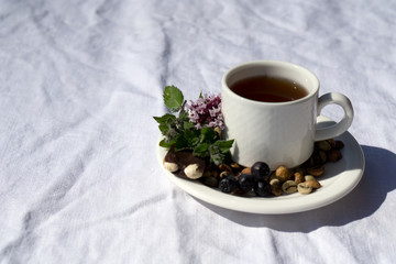 Coffee composition  with  white cup    of coffe with herb  and beans of coffe,  Chocolate,  berry, mint on  linen tableclothtable