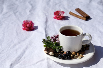 Coffee composition  with  white cup    of coffe with herb  and beans of coffe,  Chocolate,  berry, mint, flower on  linen tableclothtable