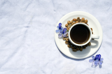 Obraz na płótnie Canvas Flat lay Coffee composition with white cup and beans of coffe and blue flower on linen tableclothtable