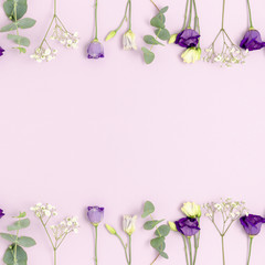 Frame made of eustoma, gypsophila flowers and eucalyptus with copy space. Floral concept on a purple pastel background.