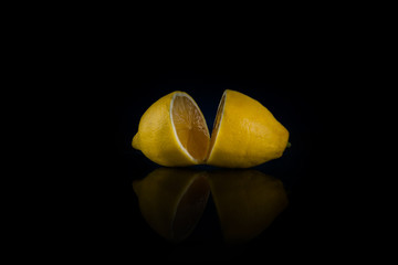 two halves of whole lemon on a black background