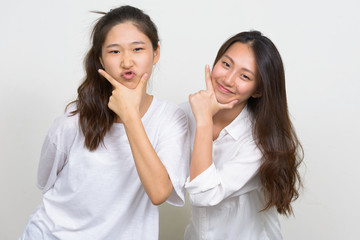 Two happy young beautiful Asian women as friends posing together
