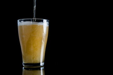 foam beer poured into a glass on a black background with copy space