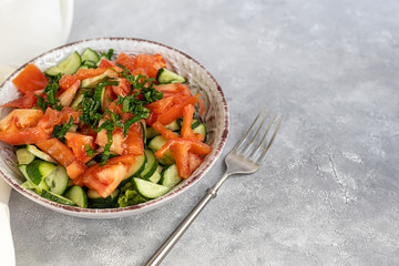Diet salad made from fresh vegetables. Cucumbers, tomatoes, green onions and chili peppers. Parsley greens. Dressed with olive oil.