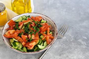 Diet salad made from fresh vegetables. Cucumbers, tomatoes, green onions and chili peppers. Parsley greens. Dressed with olive oil.