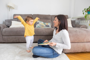 Madre leyendo un cuento educativo a su hija pequeña mientras se divierten y sonríen