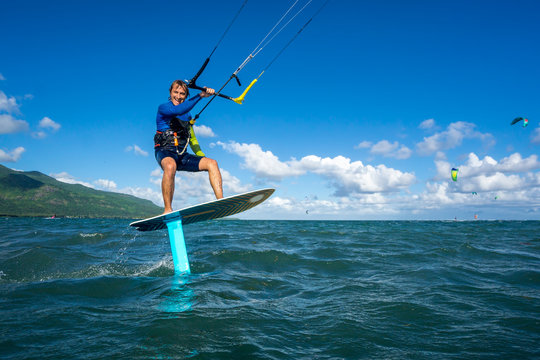 professional kiter t rides by hydrofoil on a beautiful background of mountain, spray and beautiful clouds of Mauritius