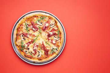 Prosciutto and arugula pizza top view on red table