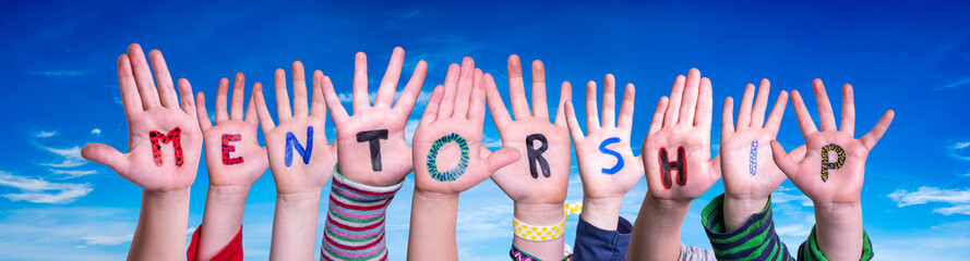 Children Hands Building Colorful English Word Mentorship. Blue Sky As Background